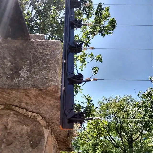 Poste de cerco eléctrico con aisladores sobre un muro perimetral en CABA