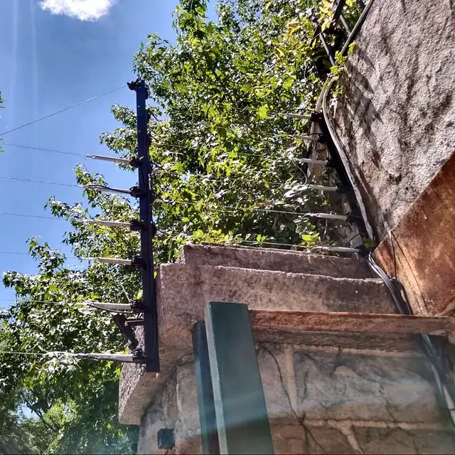 Postes de cerco eléctrico siguiendo la esquina de un muro de piedra en CABA