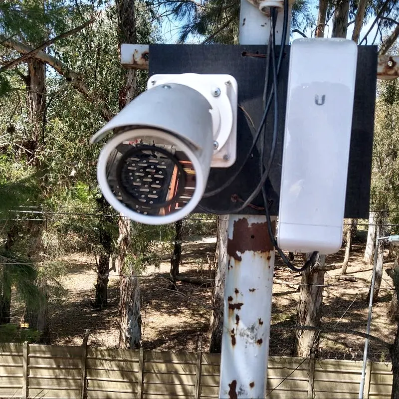Cámara PTZ motorizada con antena de enlace inalámbrico Ubiquiti en una planta industrial